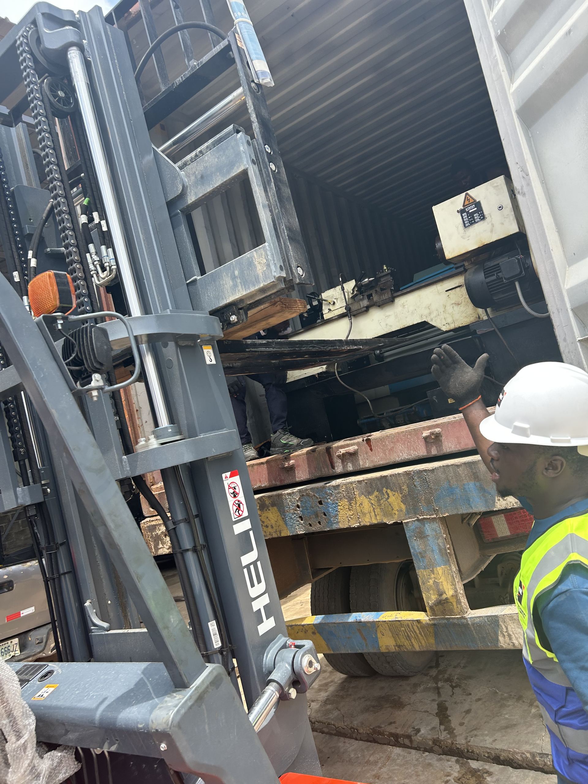 Forklift extracting a lathe machine from the shipping container