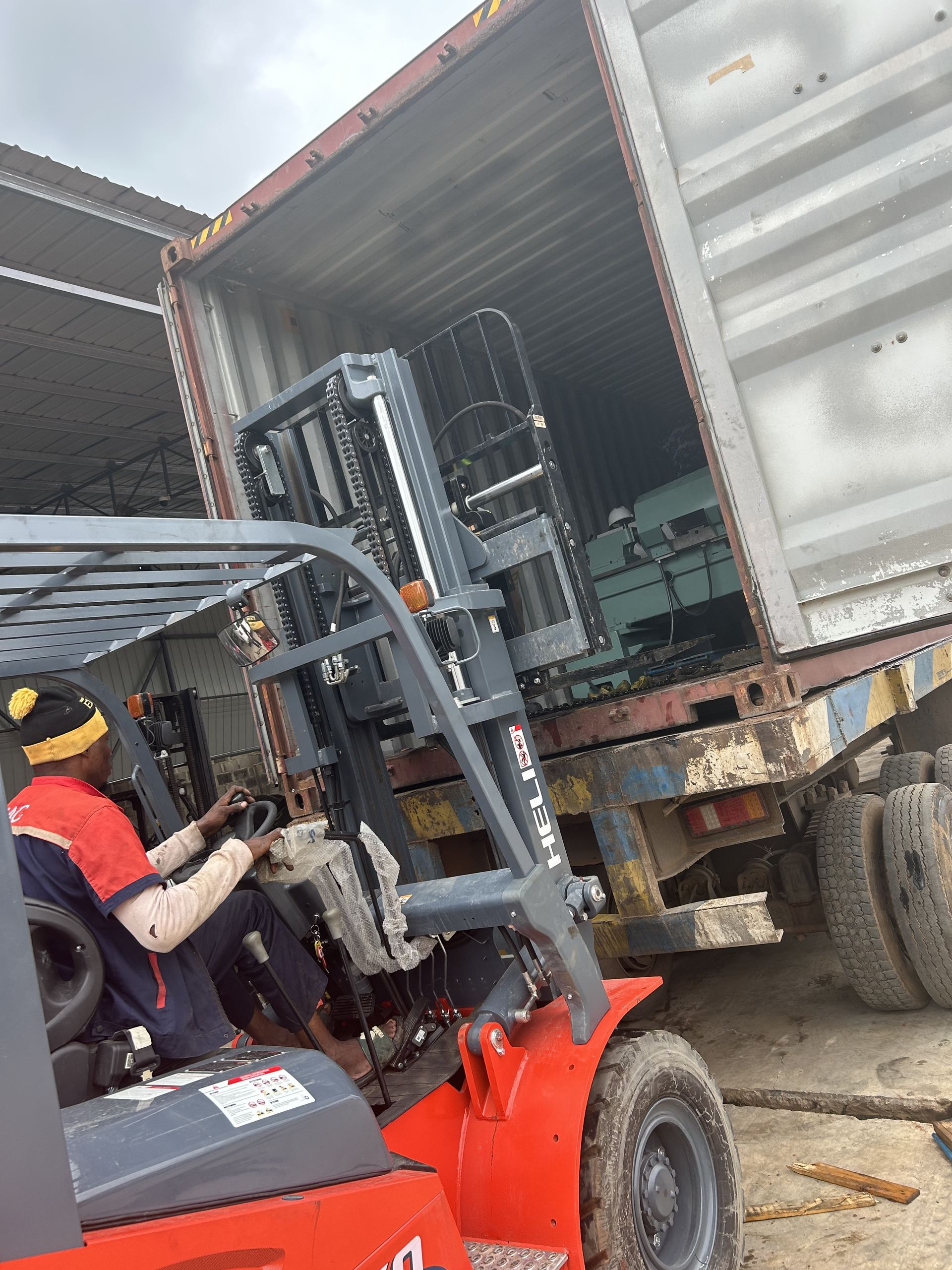 Forklift operator positioning to offload machinery from the container