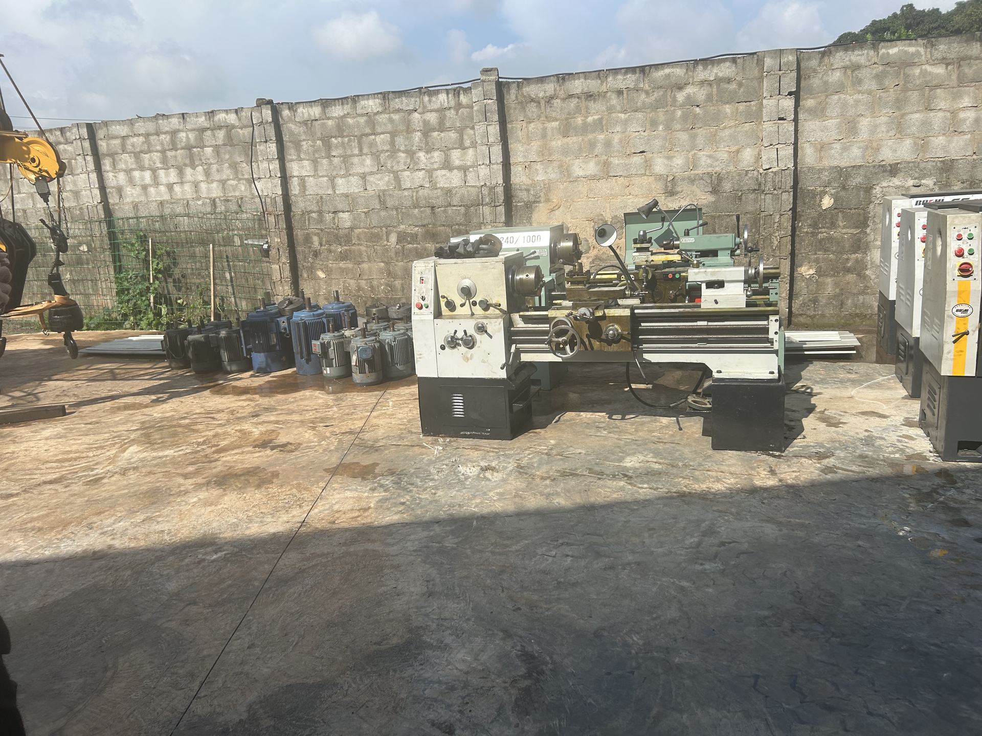 Lathe machine with spare electric motors lined up in the yard